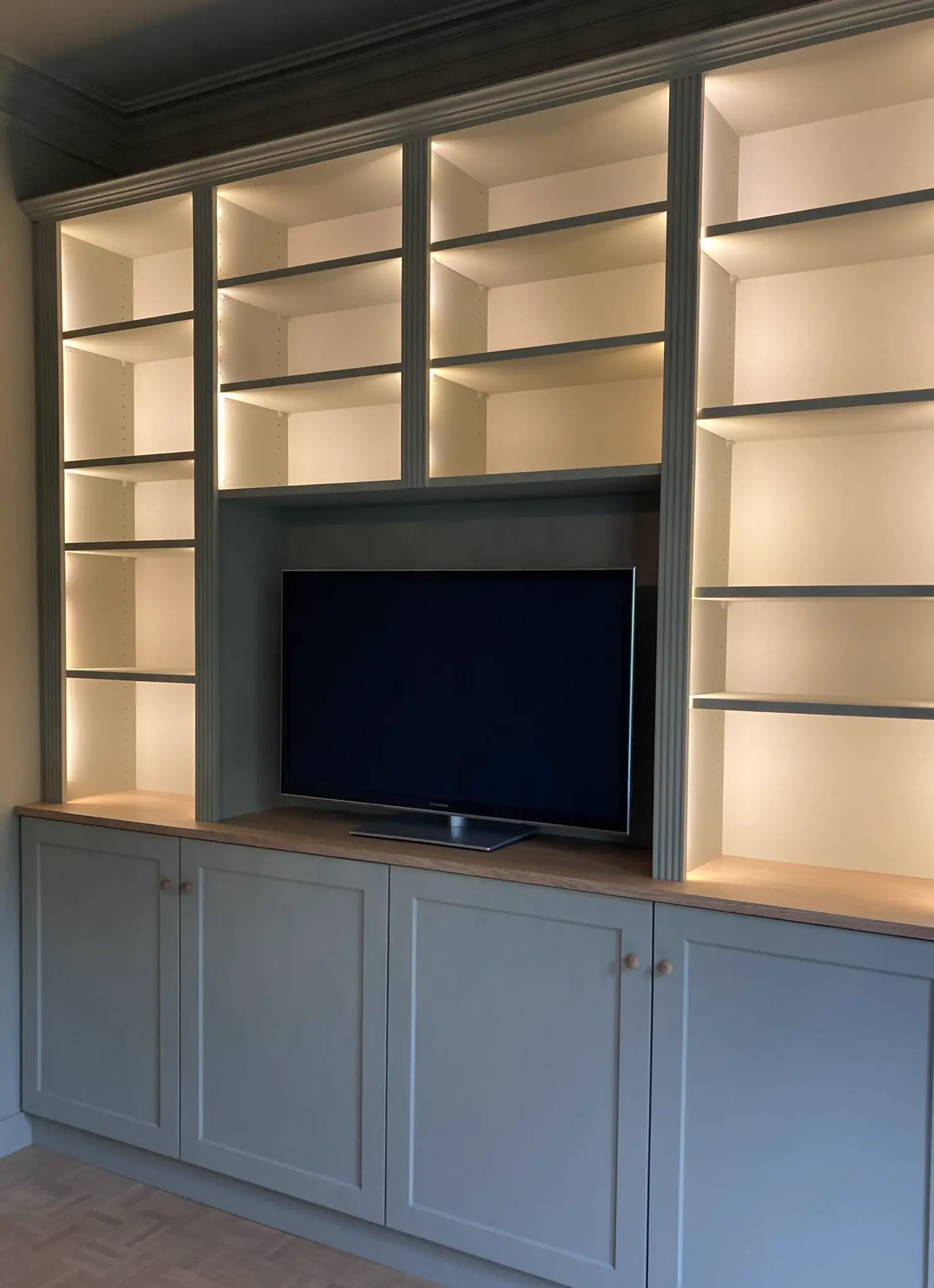 Meuble de séjour laqué gris clair, avec niches éclairées et emplacement pour téléviseur