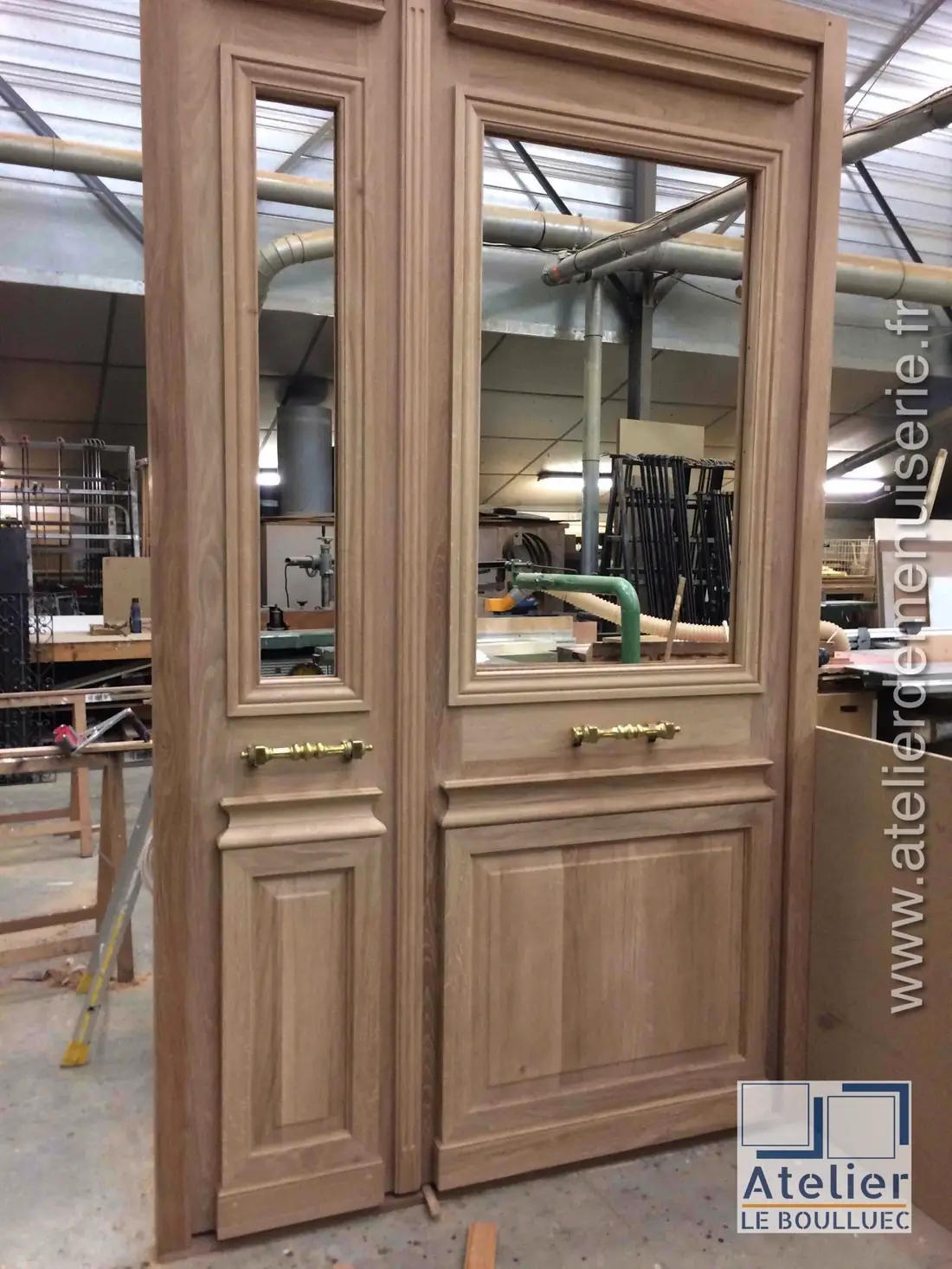 Porte à deux vantaux en chêne montée à blanc sur les établis de l’atelier