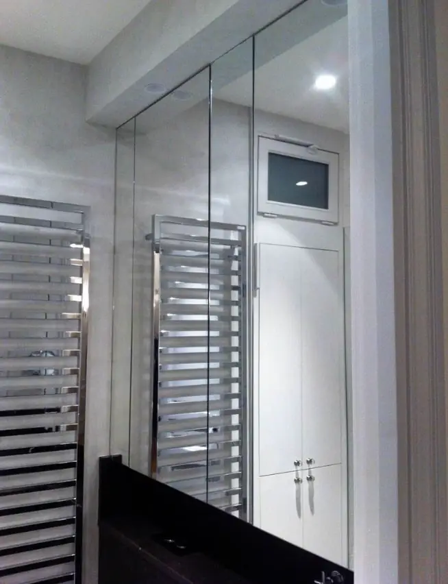 Salle de bain avec cloison vitrée, miroirs et sèche-serviettes