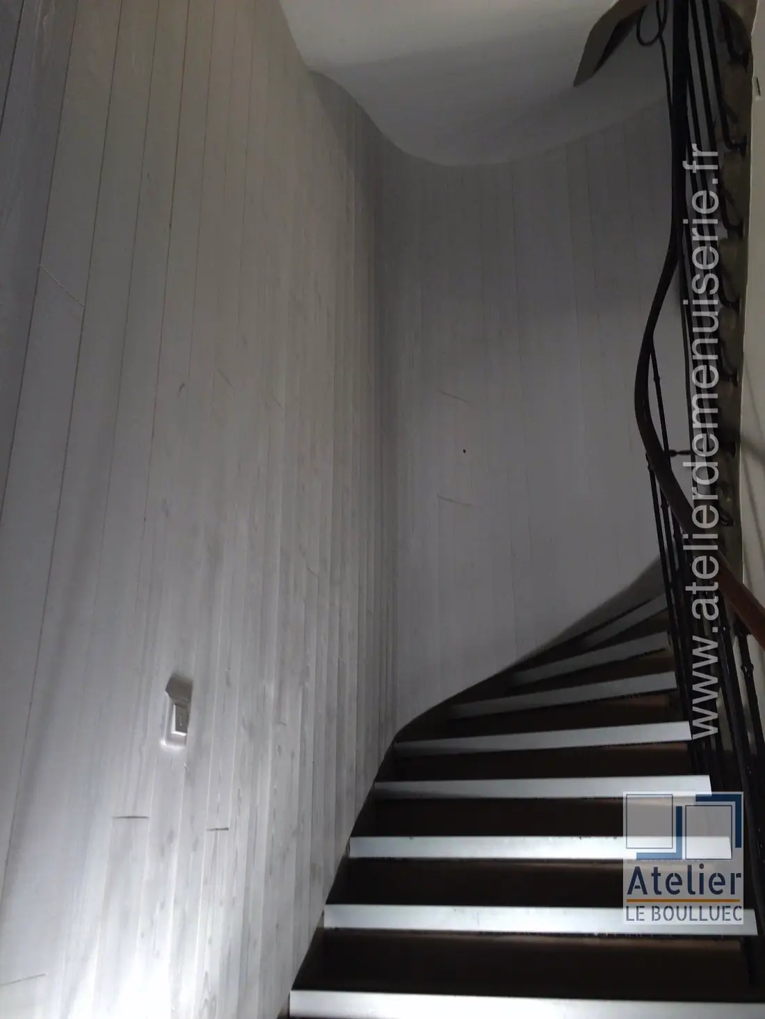 Cage d’escalier habillée de lambris, vue plongeante sur les marches