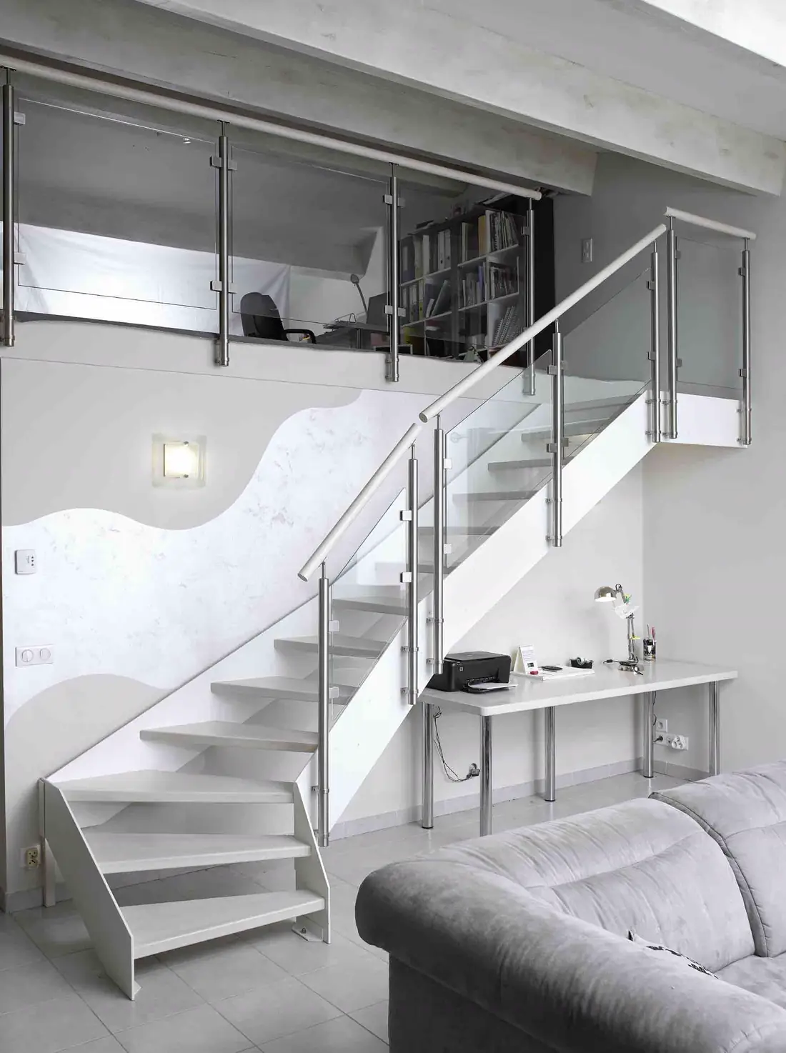 Escalier à marches blanches et balustrade inox dans un intérieur clair