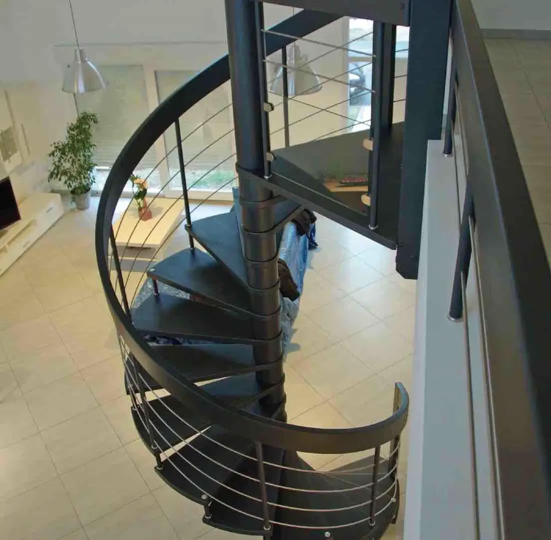 Escalier hélicoïdal en acier gris à barreaudage, dans un séjour