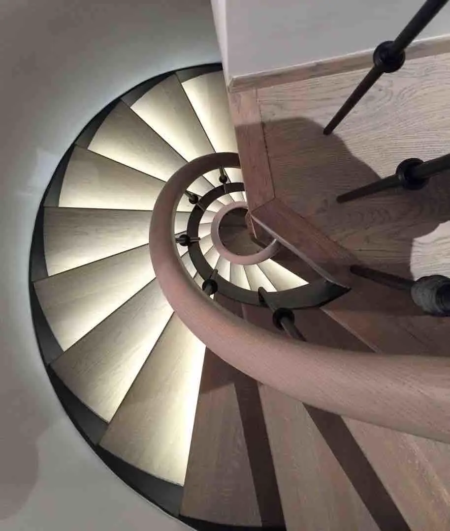Vue plongeante sur un escalier hélicoïdal en bois aux marches éclairées