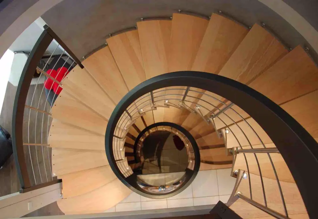Vue plongeante sur un escalier hélicoïdal en bois à garde-corps bois