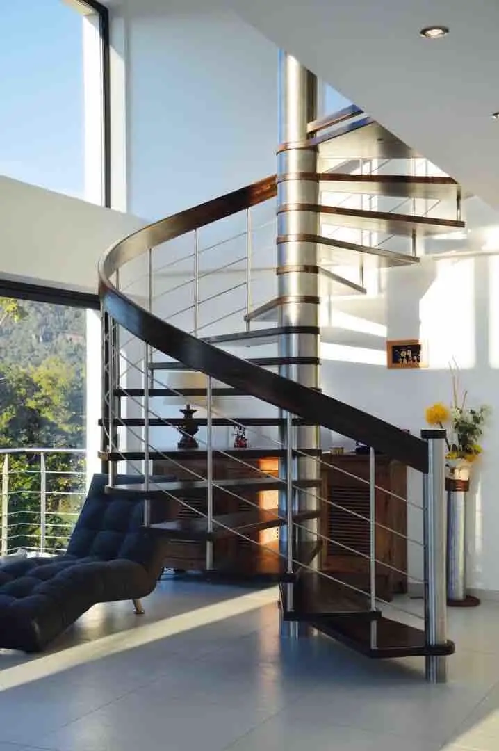 Escalier hélicoïdal en bois et acier dans un séjour à double hauteur