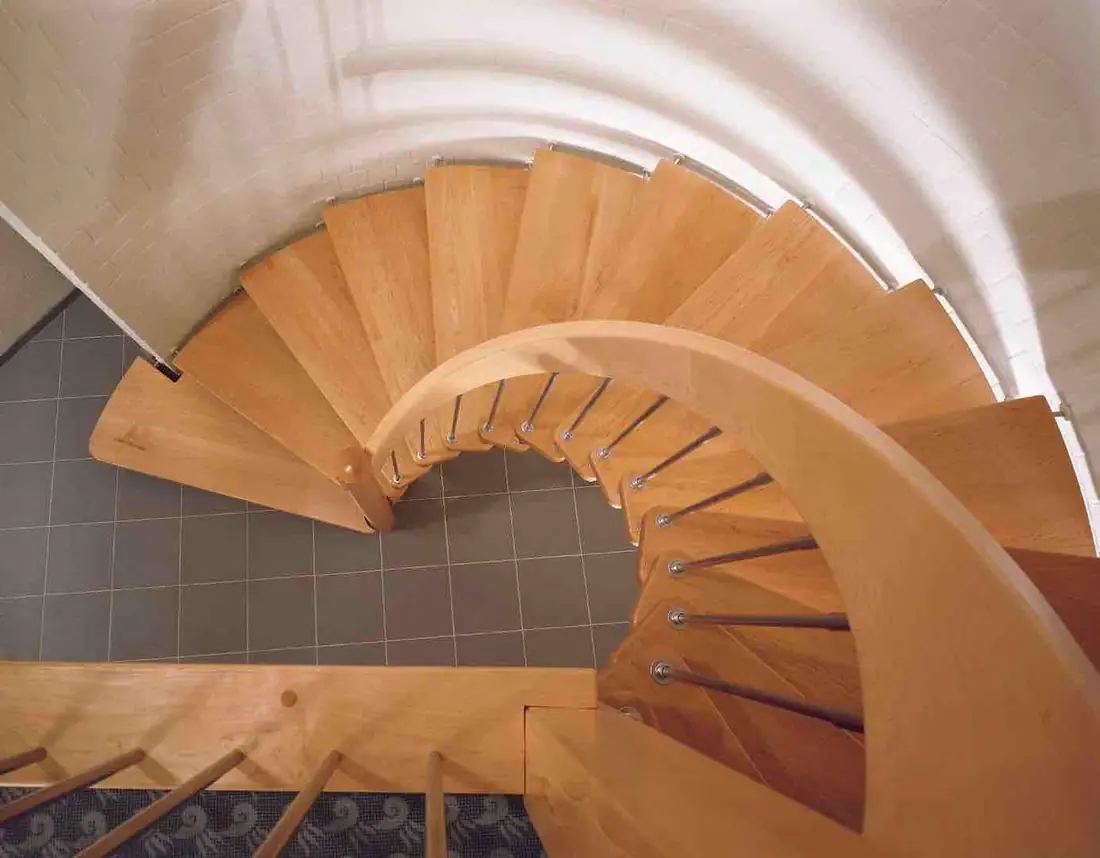 Vue plongeante sur un escalier hélicoïdal en bois clair à limon central