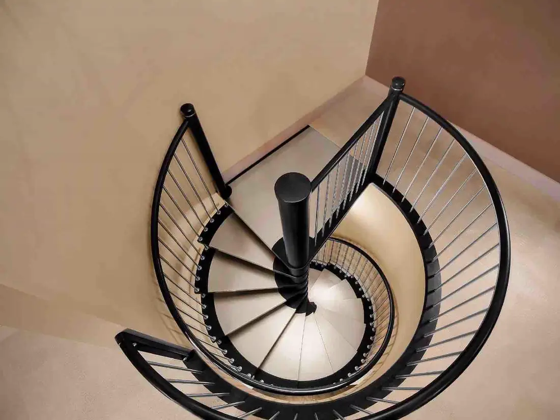 Vue plongeante sur un escalier hélicoïdal à limon acier noir et marches claires