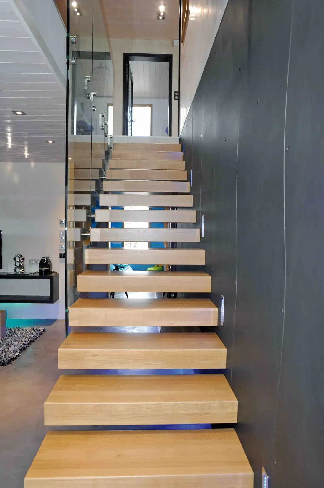 Escalier à marches suspendues éclairées par des réglettes, garde-corps en verre