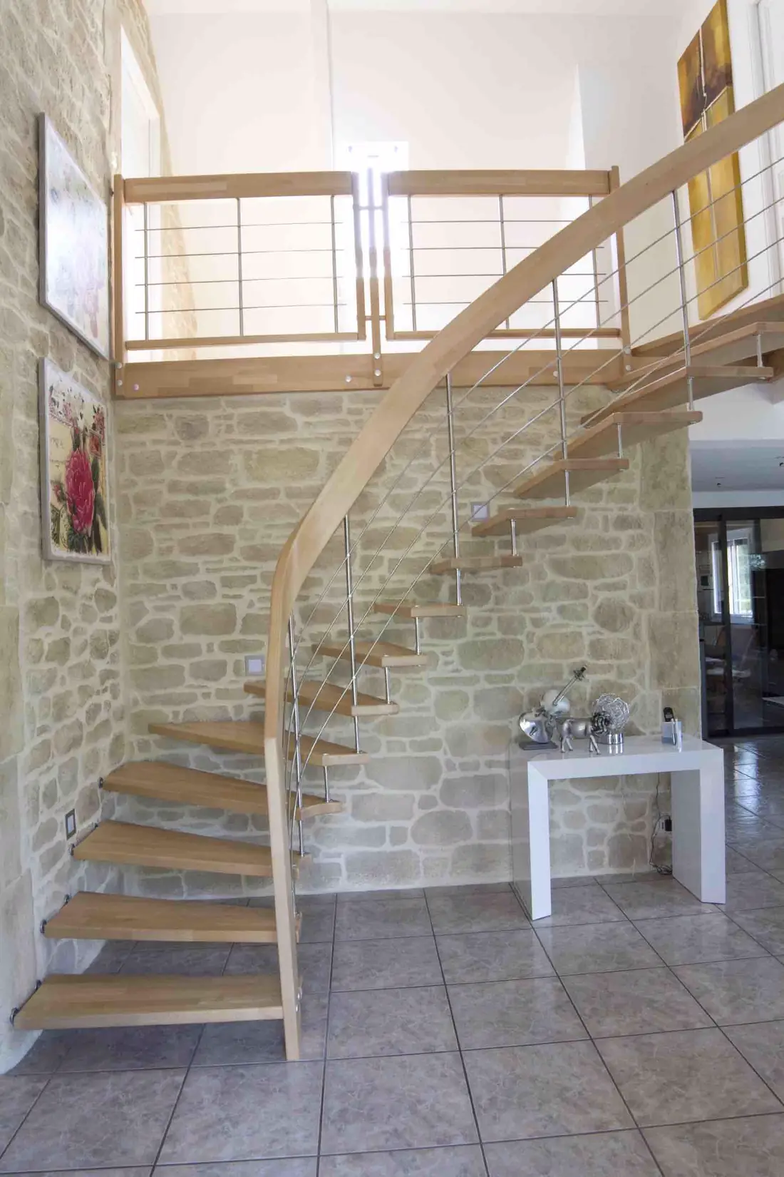 Escalier en bois quart tournant à balustrade inox, devant un mur en pierre