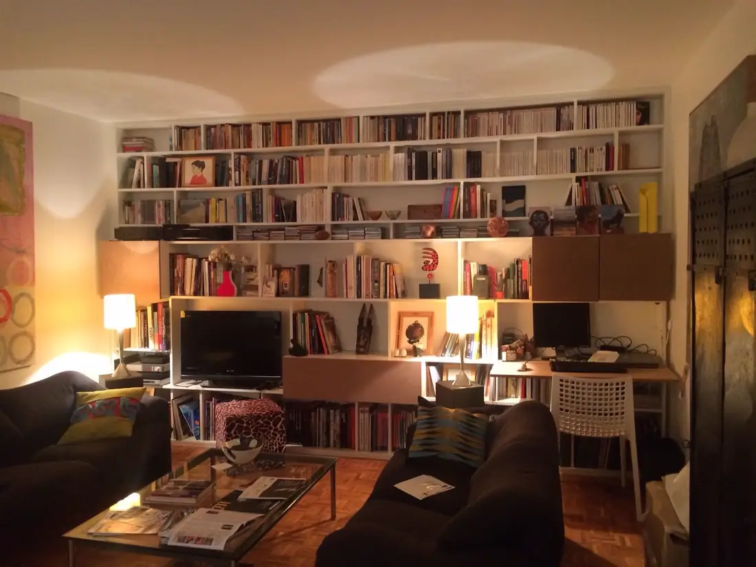 Bibliothèque murale blanche à caissons garnie de livres, dans un salon
