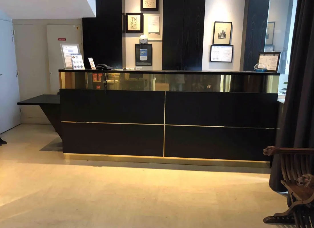 Banque d’accueil laquée noire à plateau débordant, dans le hall d’un hôtel