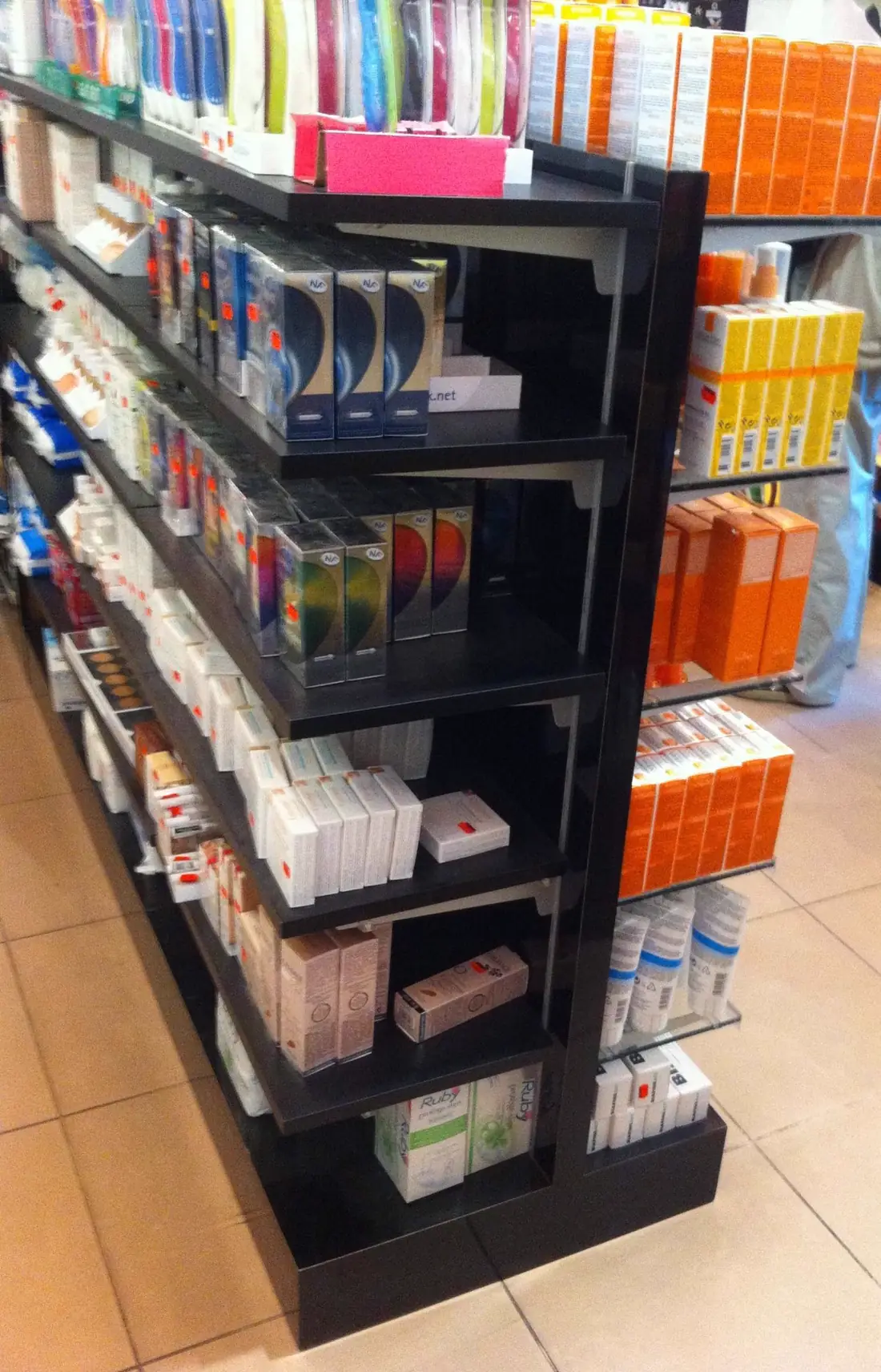 Présentoir en aggloméré stratifié noir brillant garni de produits, en pharmacie
