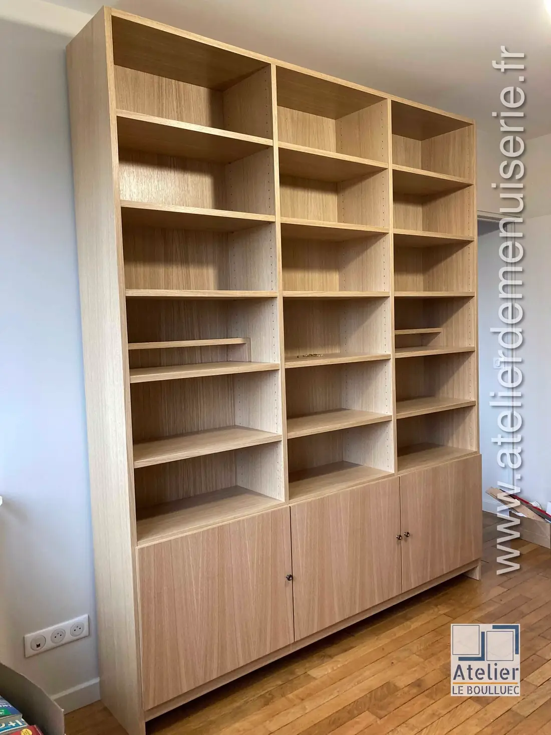 Bibliothèque en panneaux plaqués chêne clair montant jusqu’au plafond