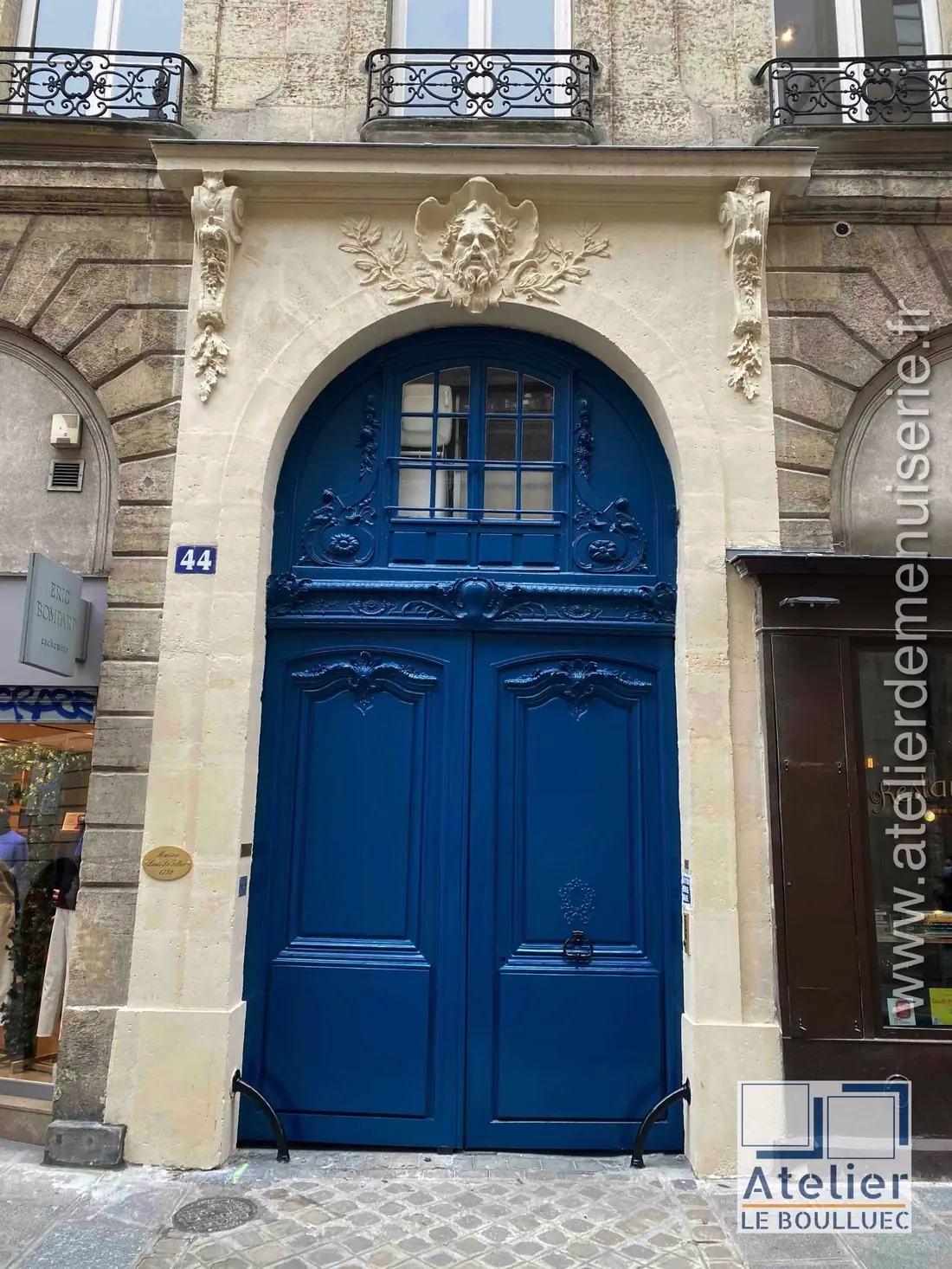 Porte cochère bleue sous un arc à mascaron, après restauration