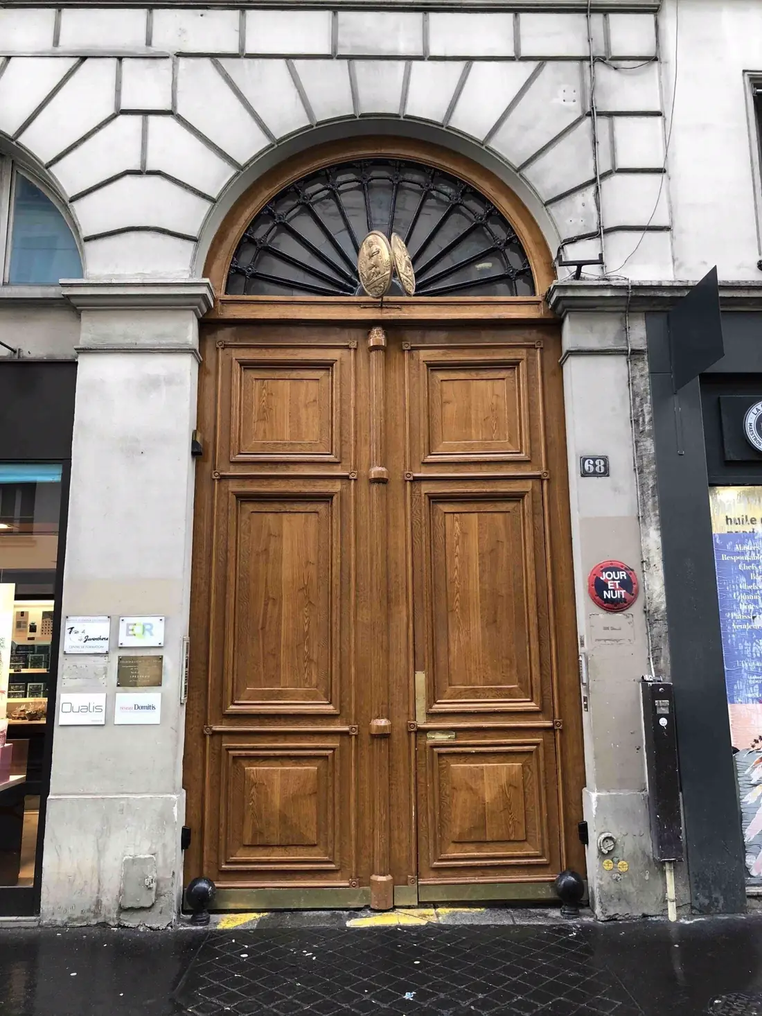 Porte cochère monumentale en chêne clair sous un arc surbaissé, reposée et peinte