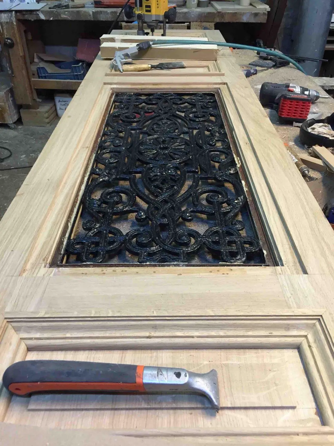 Vantail en chêne en cours de façonnage à l’atelier, autour d’une grille ancienne remployée