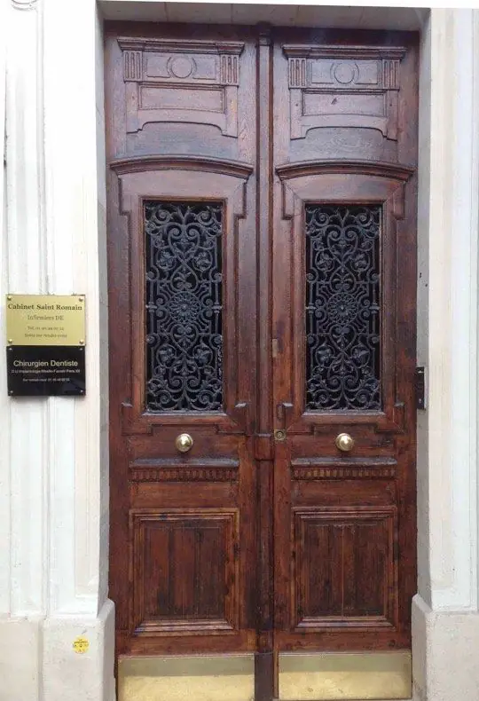 Porte d’immeuble à deux vantaux en chêne foncé, panneaux sculptés et grilles en fonte