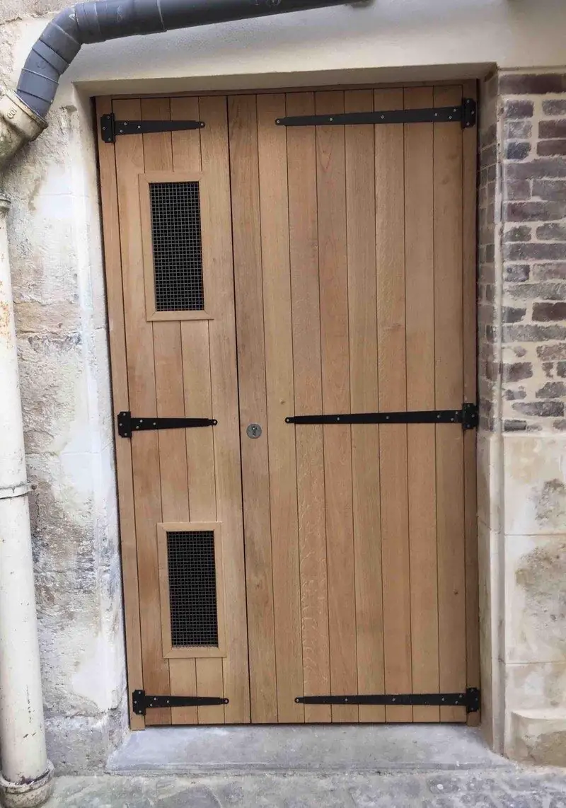 Porte de cave en chêne à lames verticales et pentures forgées, encadrement de pierre
