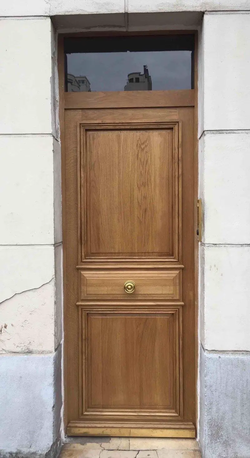 Porte pleine en chêne vernis surmontée d’une imposte vitrée