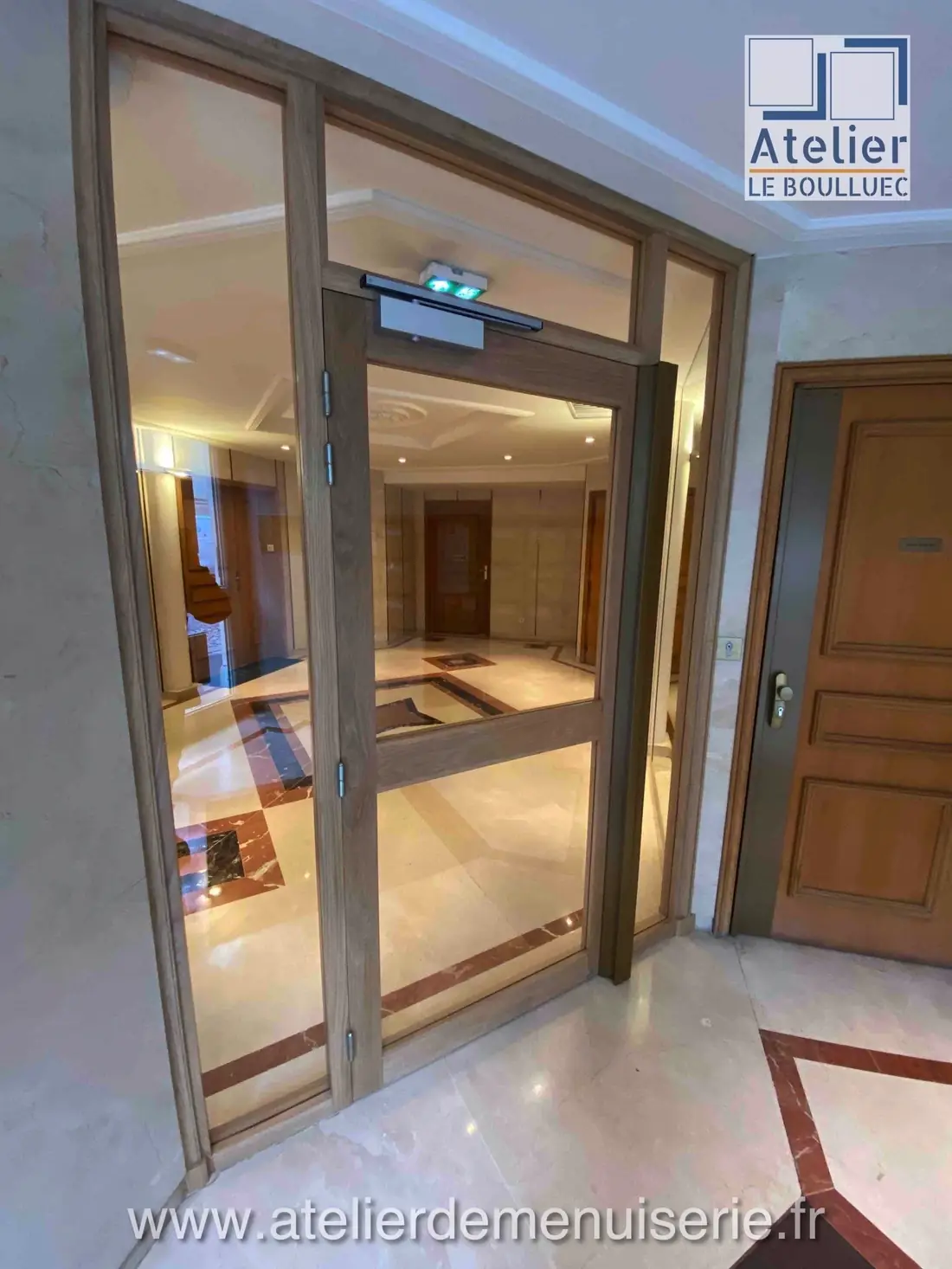 Porte sas vitrée teintée sombre dans le hall d’un immeuble parisien