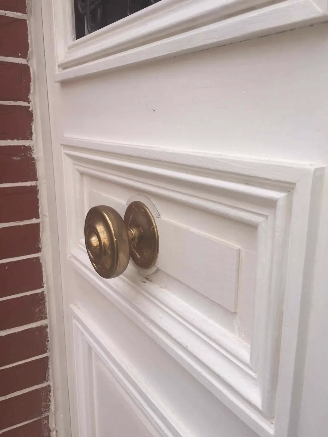Détail d’un bouton de tirage en laiton sur une porte peinte en blanc, moulurée