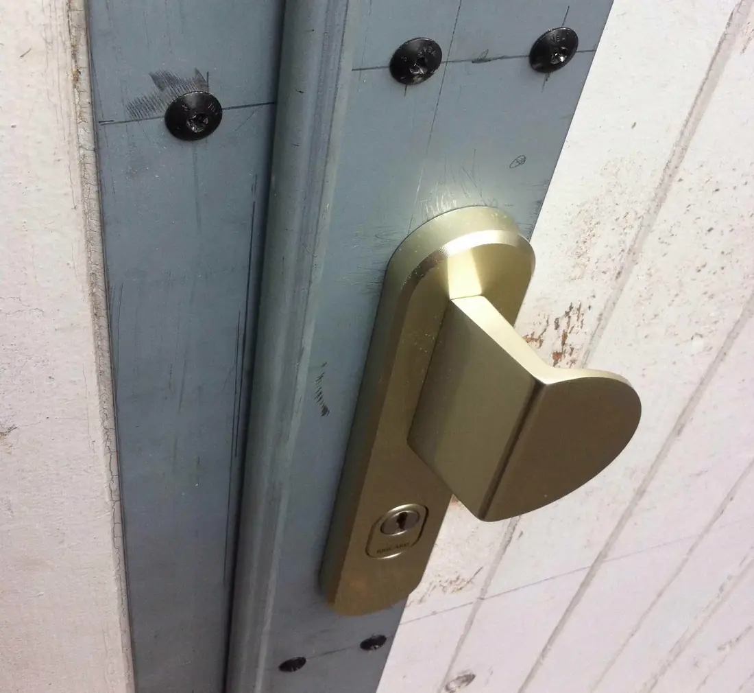Béquille en laiton brossé montée sur une porte peinte claire, vue rapprochée