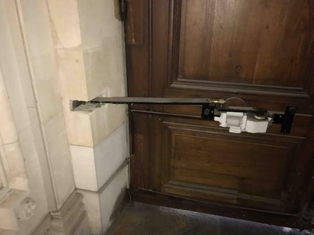 Bras à compas de motorisation fixé en imposte sur une porte cochère en chêne