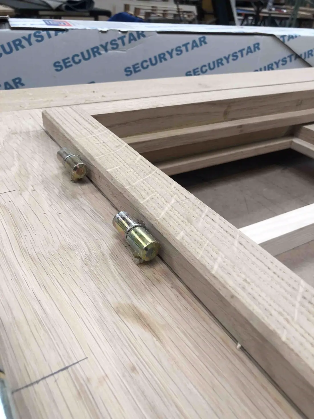 Châssis en cours de façonnage à l’atelier, paumelles posées et vitrage protégé